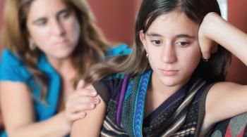 An upset girl is comforted by an adult woman.